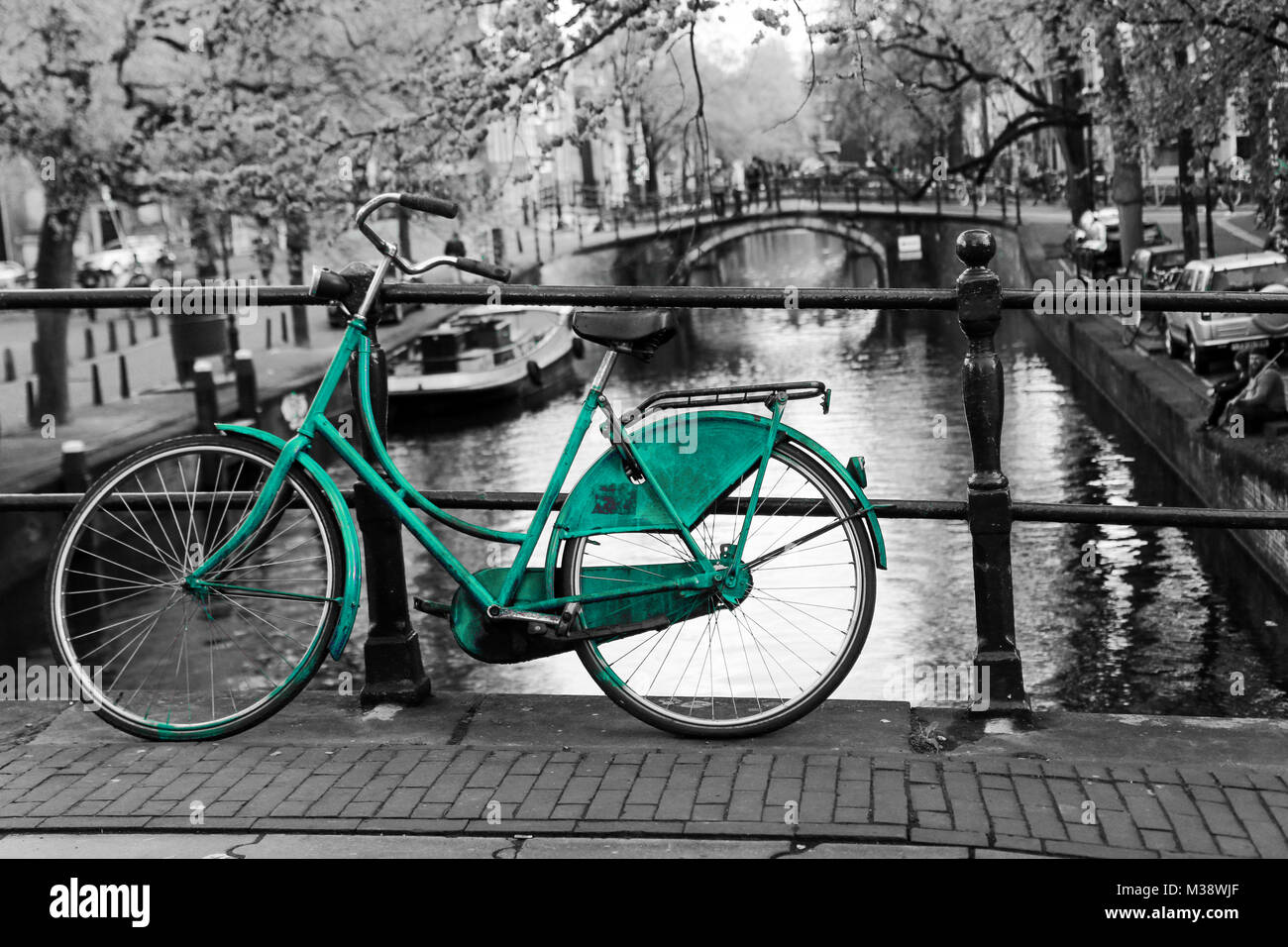 Una foto di un solitario azure bici sul ponte sul canale di Amsterdam. Lo sfondo è bianco e nero. Foto Stock