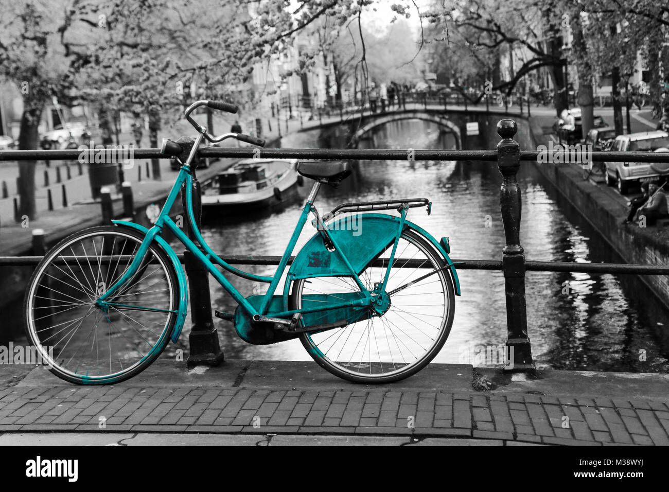 Una foto di un solitario azure bici sul ponte sul canale di Amsterdam. Lo sfondo è bianco e nero. Foto Stock