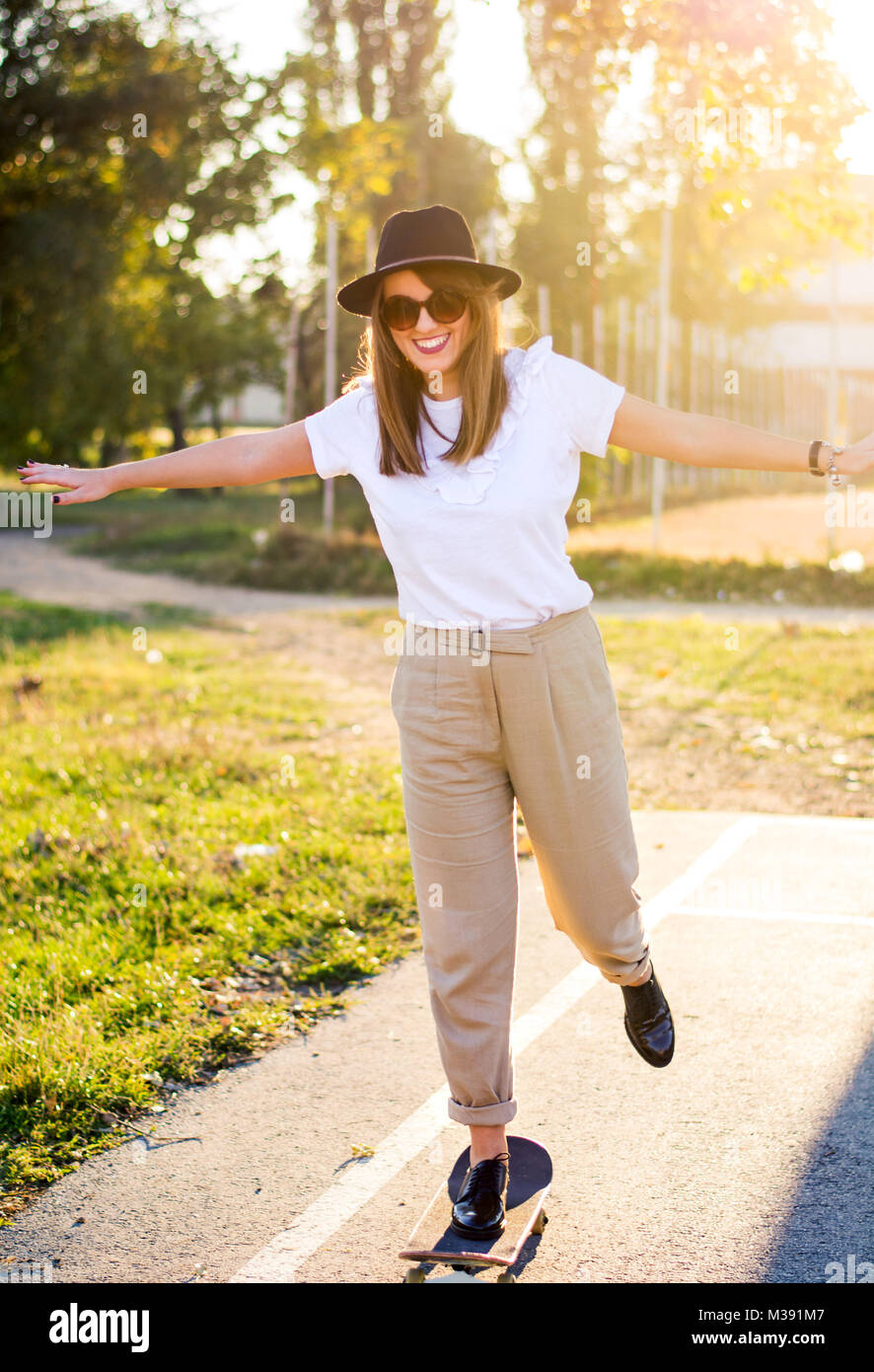 Equitazione femmina uno skateboard al tramonto. Città uno stile di vita urbano Foto Stock