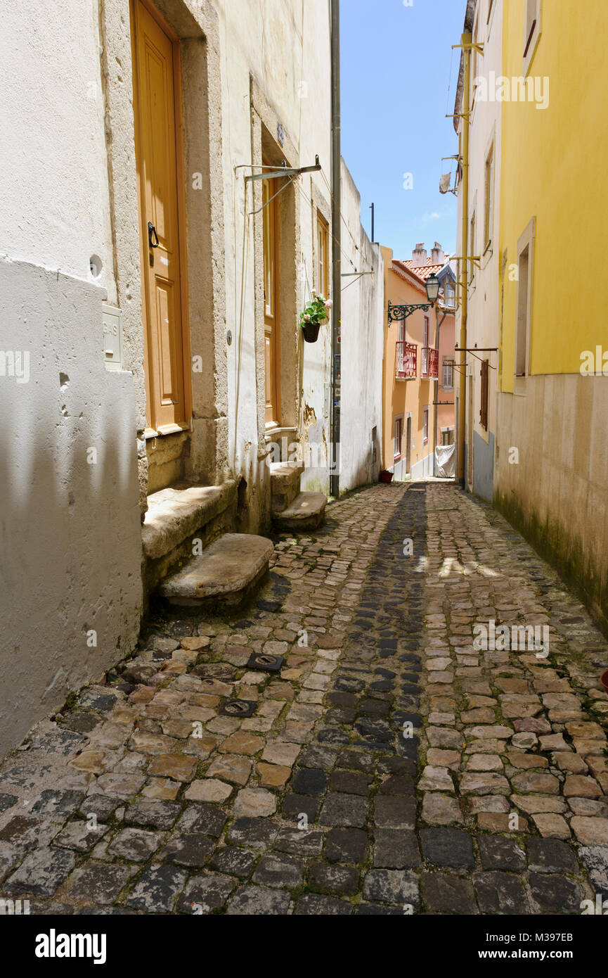 Un tipico acciottolato stretto Street nel quartiere di Alfama, Lisbona, Portogallo Foto Stock