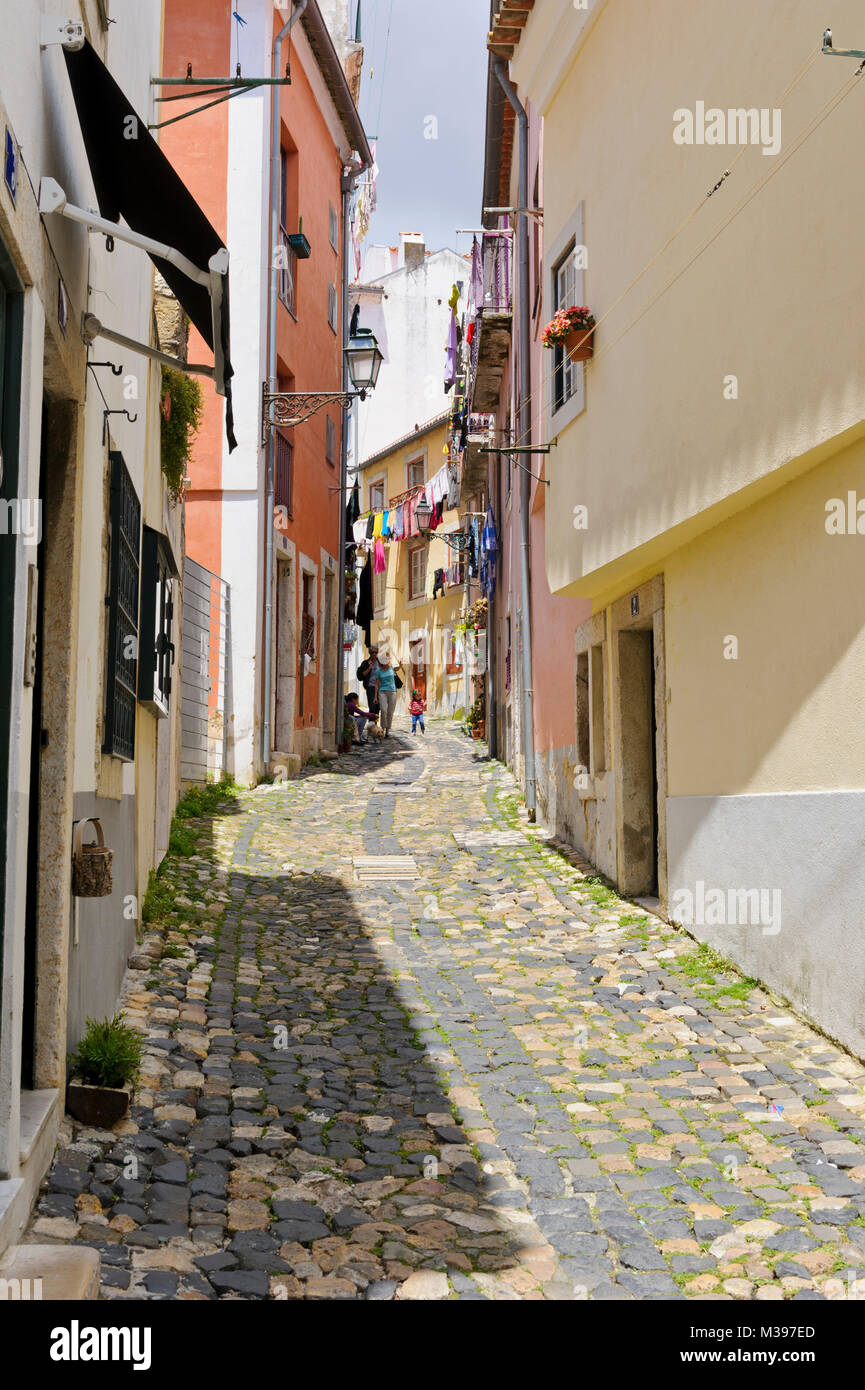 Un tipico acciottolato stretto Street nel quartiere di Alfama, Lisbona, Portogallo Foto Stock
