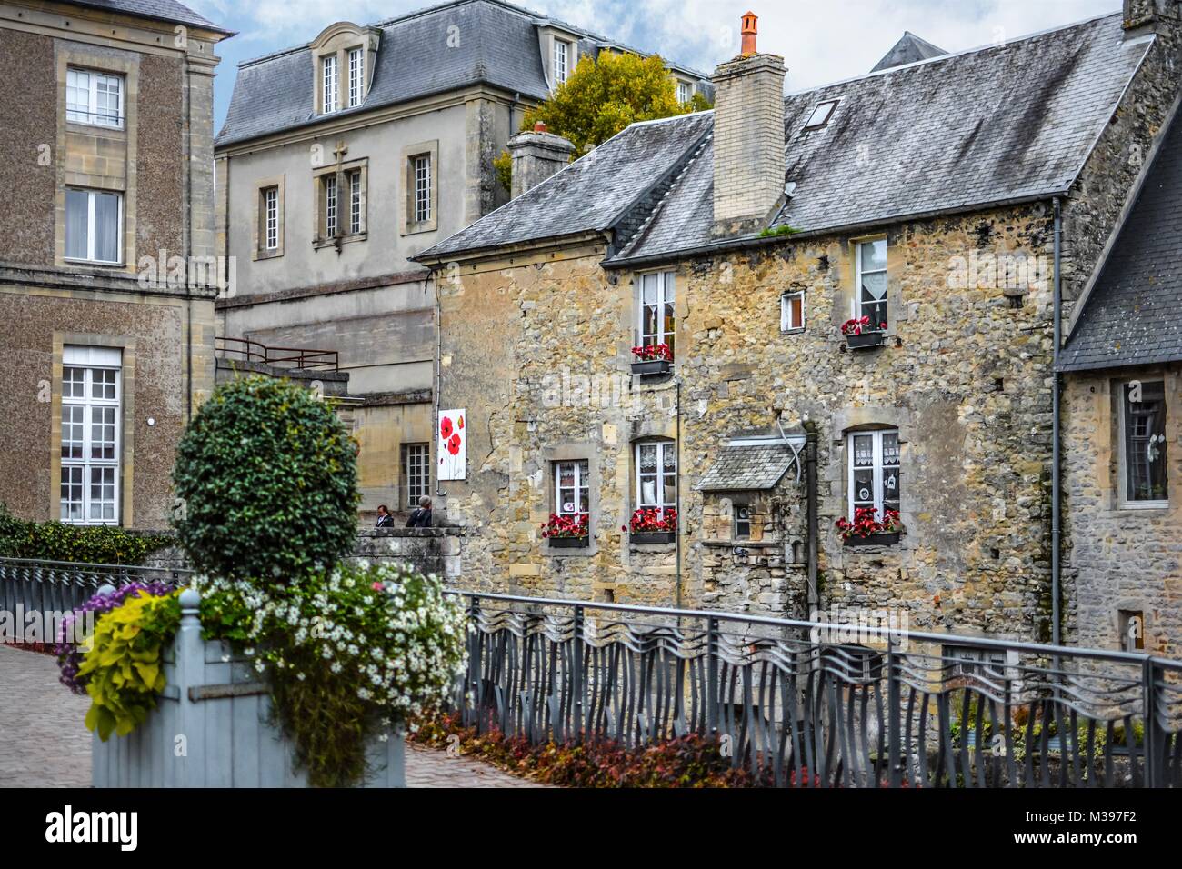 Pittoresca piazza nel villaggio storico di Bayeux in Francia con le case di pietra e finestre con fiori colorati in scatole Foto Stock