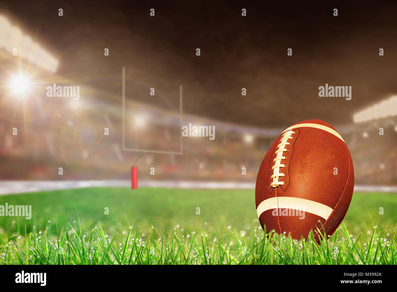 Il football americano sul campo in erba luminosamente illuminata outdoor stadium con focus sul primo piano e profondità di campo sullo sfondo. Lente deliberata fl Foto Stock