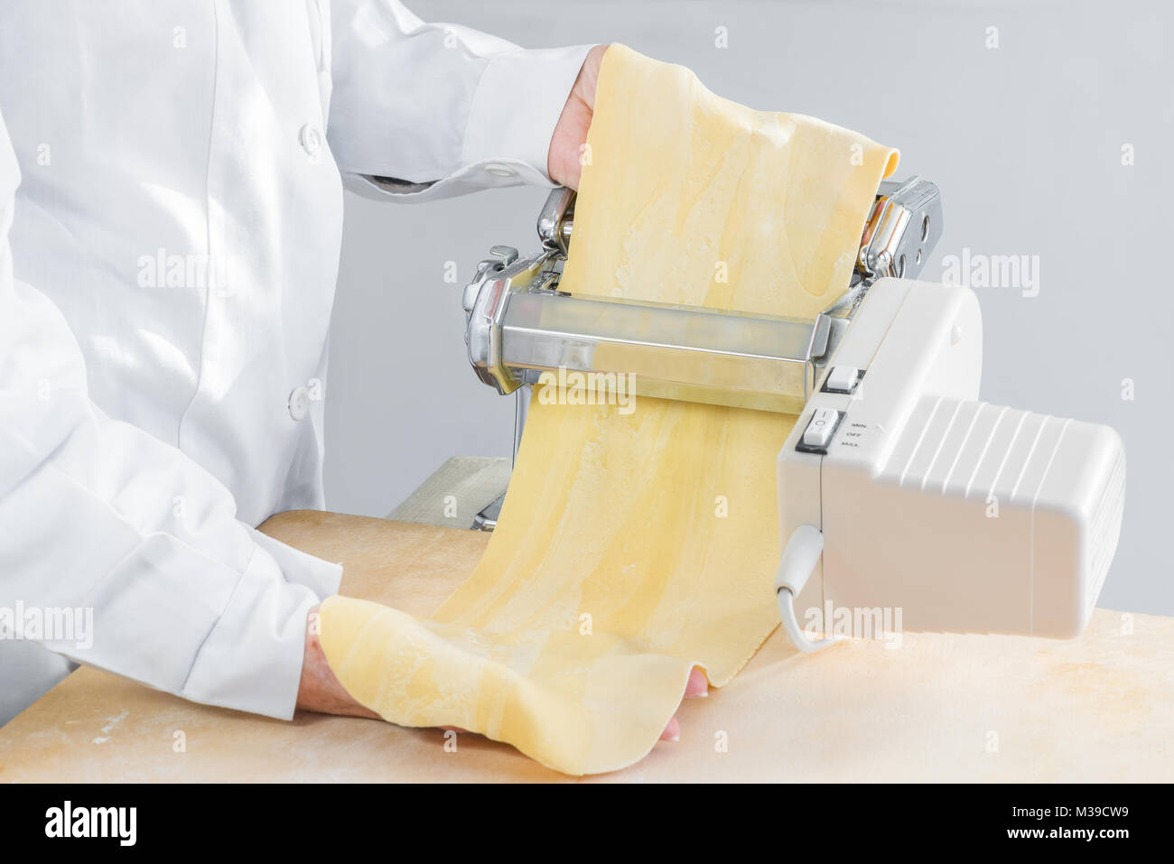 Preparazione della pasta con una macchina elettrica per rendere fresca  pasta fatta in casa (tortellini, tortelli). Laminazione di un impasto  alimentare attraverso una macchina per la pasta Foto stock - Alamy