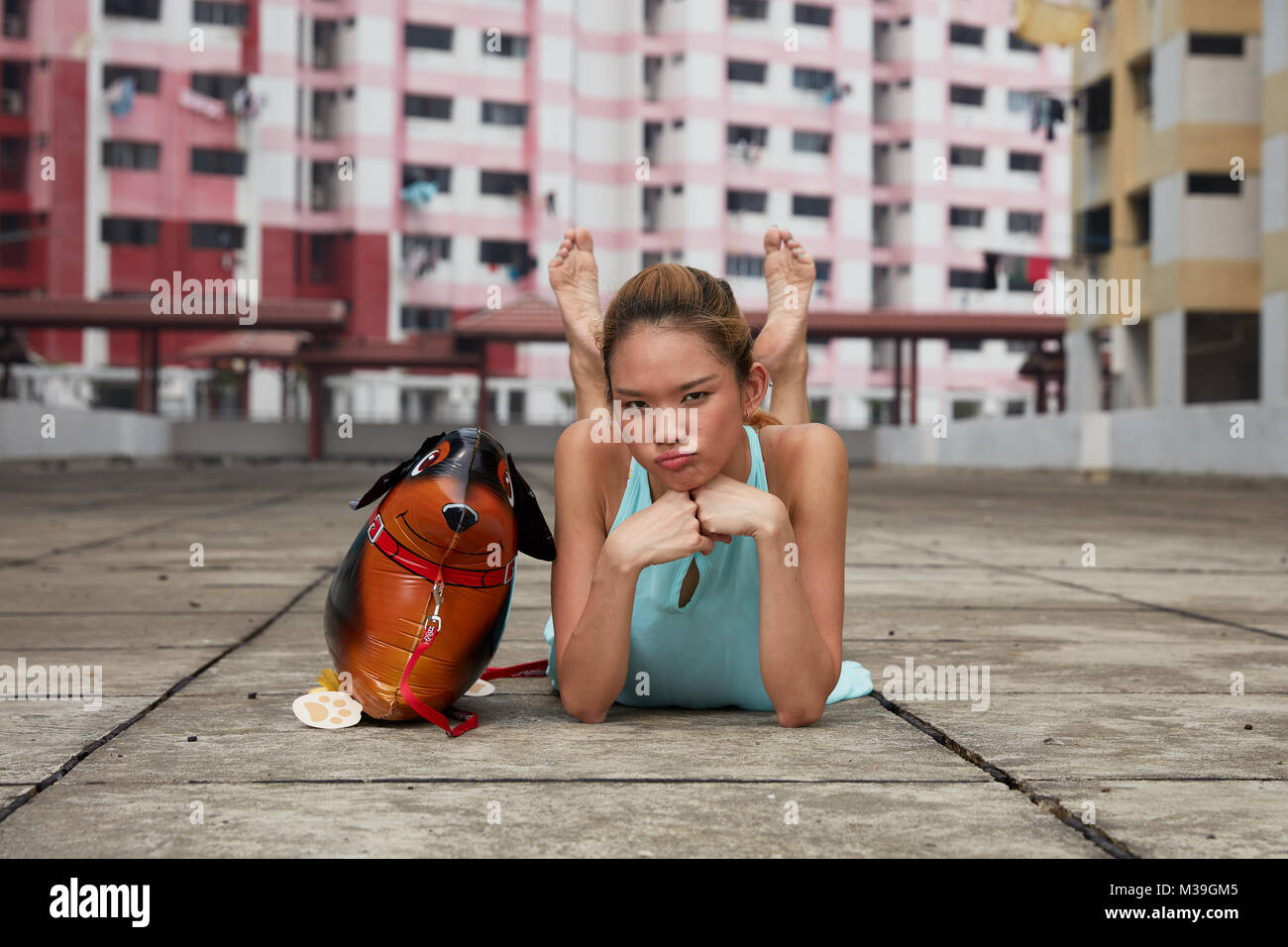 Happy fun-amare giovane ballerino femmina con palloncino giocattolo cane a Rochor Centre, Singapore. Questi edifici colorati sono punto di riferimento storico. Foto Stock
