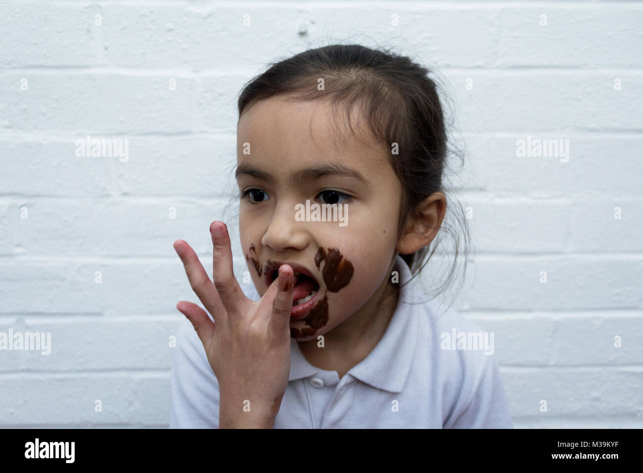 Bambino mangiare il cioccolato con il disordine sulla faccia Foto Stock