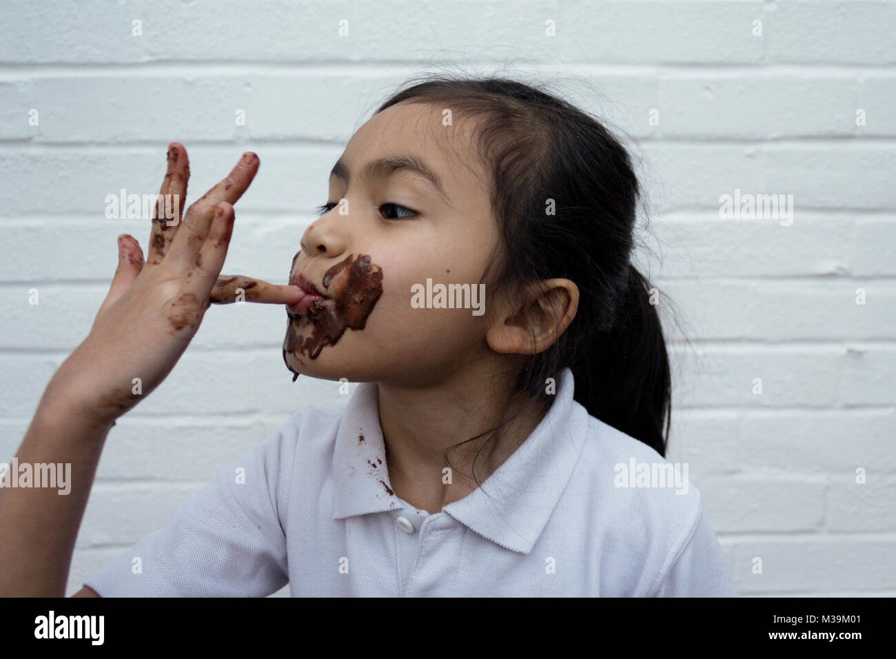 Bambino mangiare il cioccolato con il disordine sulla faccia Foto Stock