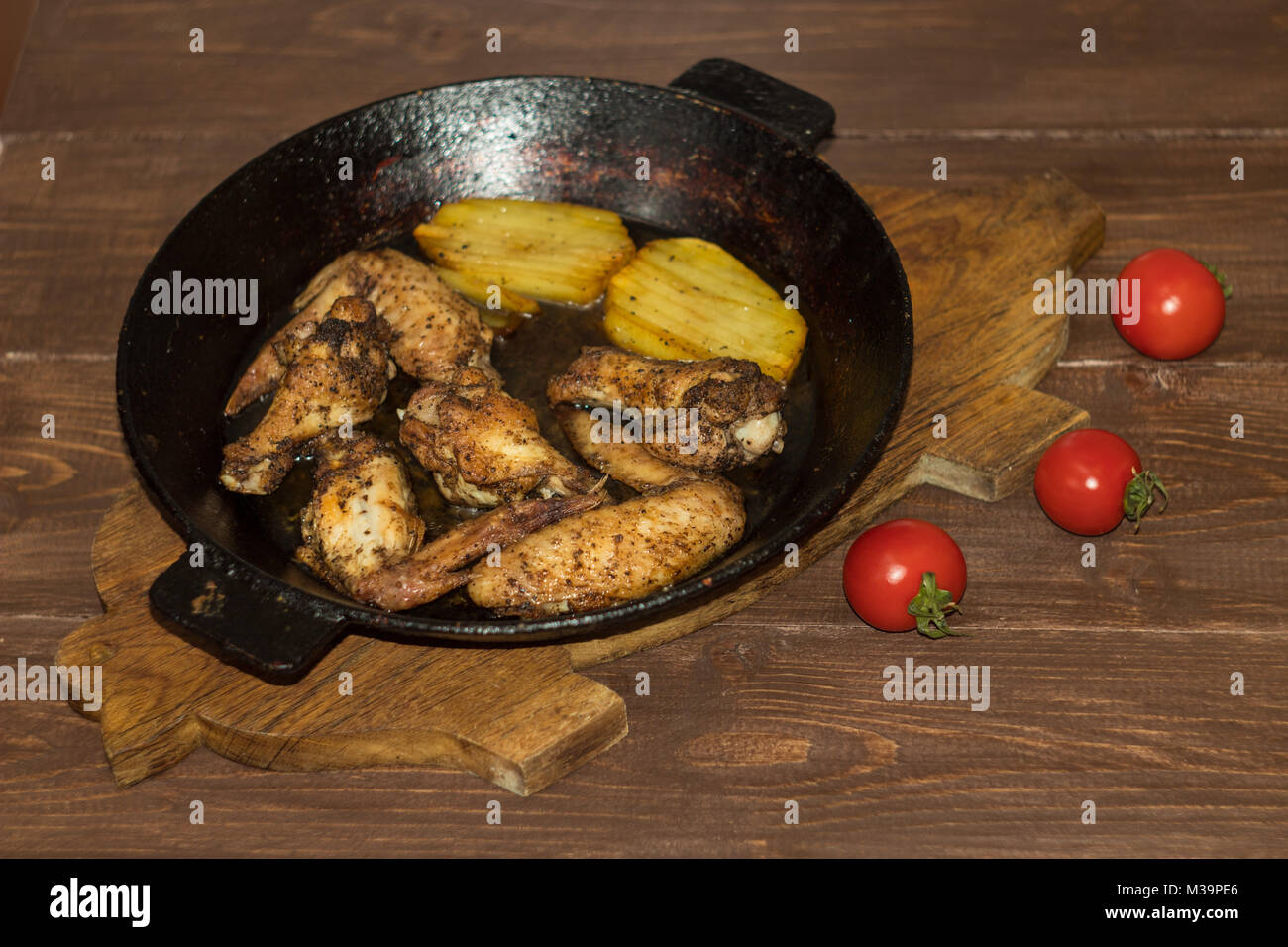 Ali di pollo con patate fritte in padella Foto Stock