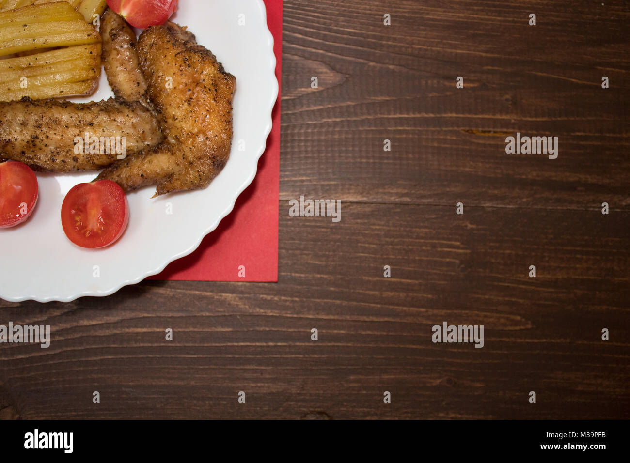 Ali di pollo con patate steso su una piastra Foto Stock