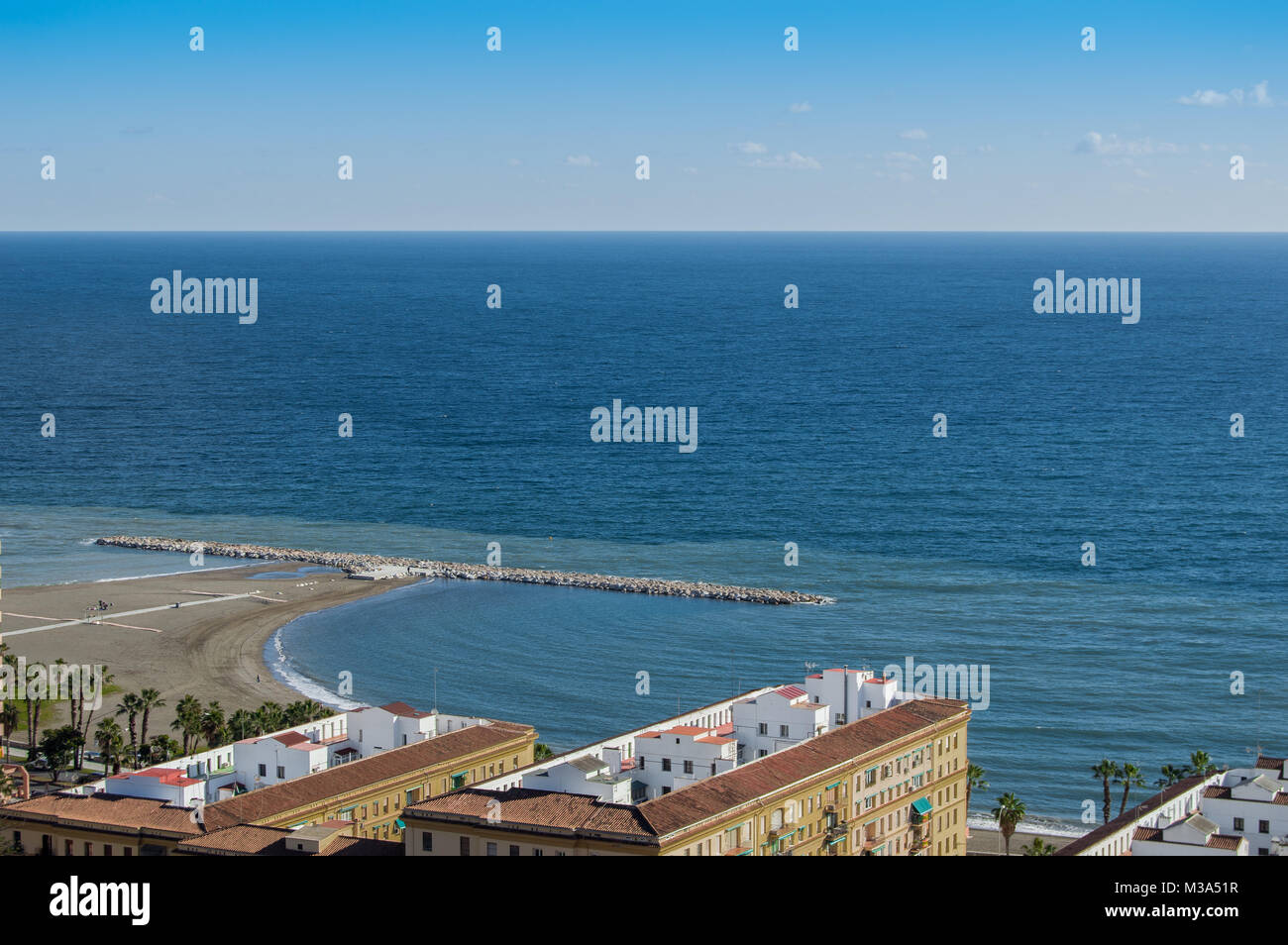 Il paesaggio di frangiflutti e di edifici in spiaggia Malagueta nella città di Malaga, Andalusia, Spagna. Bellissime vedute urbane del porto in un giorno chiaro. Foto Stock