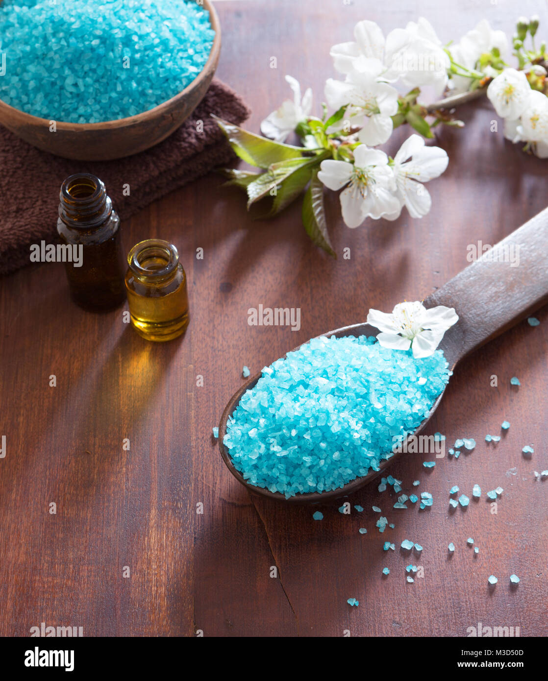Concetto di Spa. Bagno minerale sali, gel doccia, asciugamani e fiori di primavera sulla tavola di legno. Foto Stock
