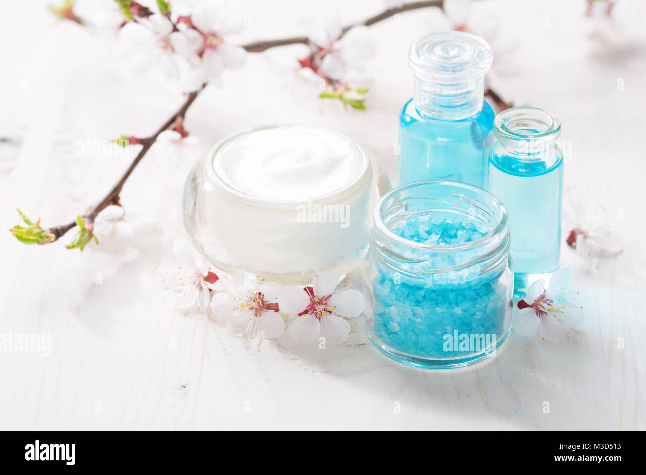 Bagno minerale sali, crema, gel per la doccia e fiori sul tavolo di legno. DOF poco profondo. Focus sul sale. Foto Stock