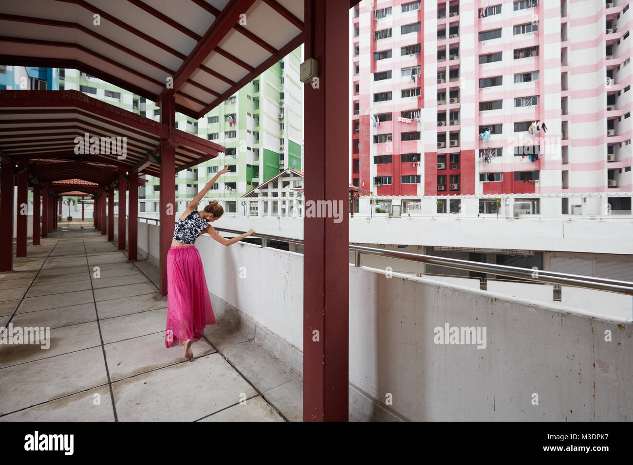 Felice, gratuito, giovane ballerino femmina a Rochor Centre, Singapore. Edificio sono una parte del centro storico di punto di riferimento come si fanno strada per expressway. Foto Stock