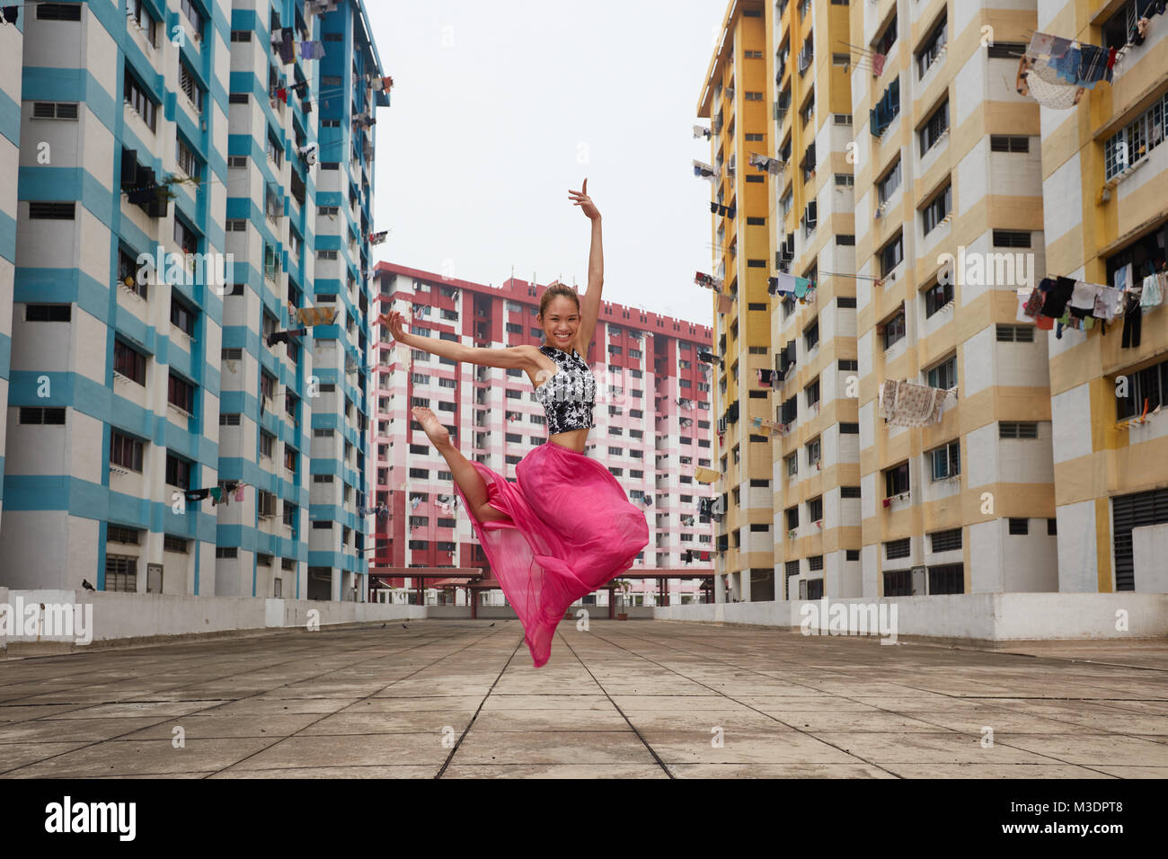 Felice, gratuito, giovane ballerino femmina a Rochor Centre, Singapore. Edificio sono una parte del centro storico di punto di riferimento come si fanno strada per expressway. Foto Stock