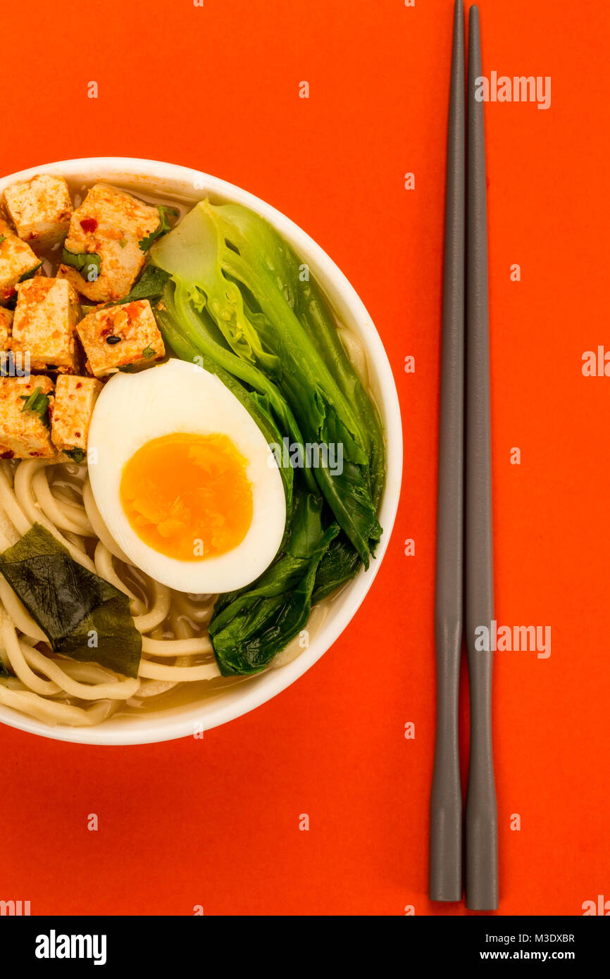 In stile giapponese tofu vegetariani Noodle Ramen zuppa o brodo contro uno sfondo rosso Foto Stock