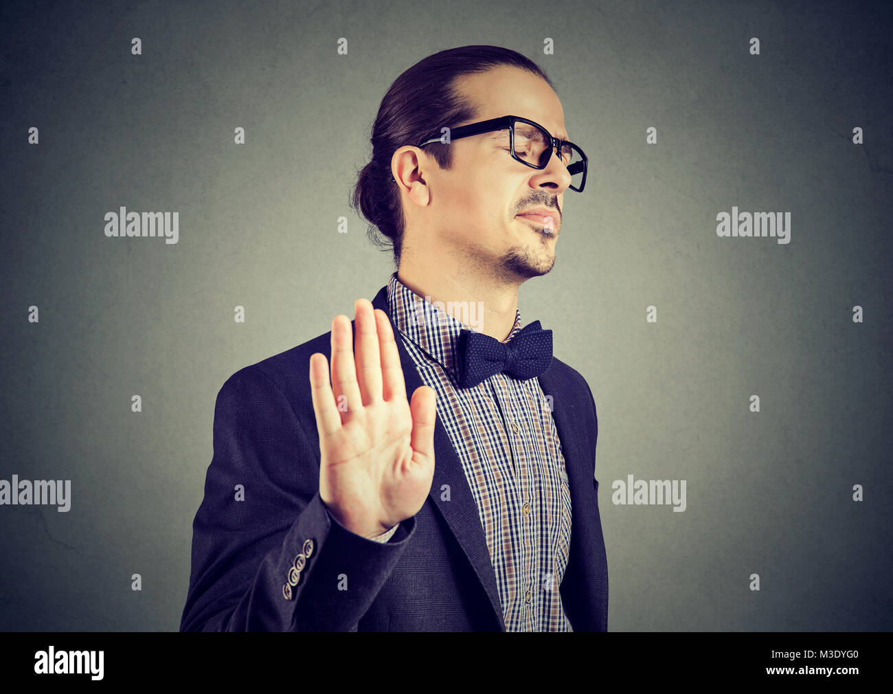 Giovane uomo elegante in occhiali fermare con la mano mentre guardando infastiditi e insultato. Foto Stock