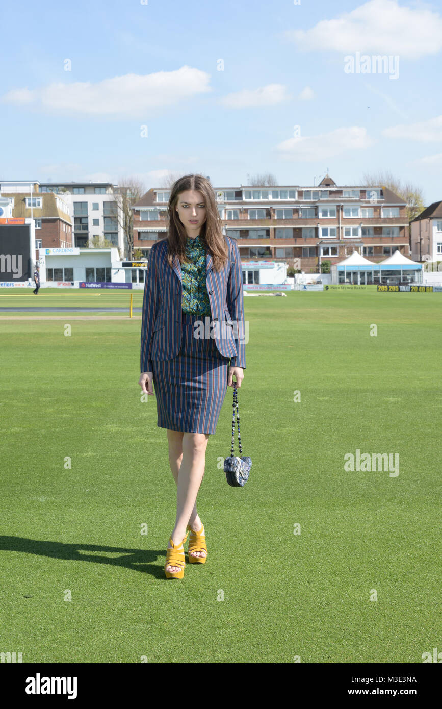 Una bella ragazza che indossa un tailored elegante abito modellato è a Cricket Ground su una bella giornata splendente- lei è fiducioso e assertivi Foto Stock