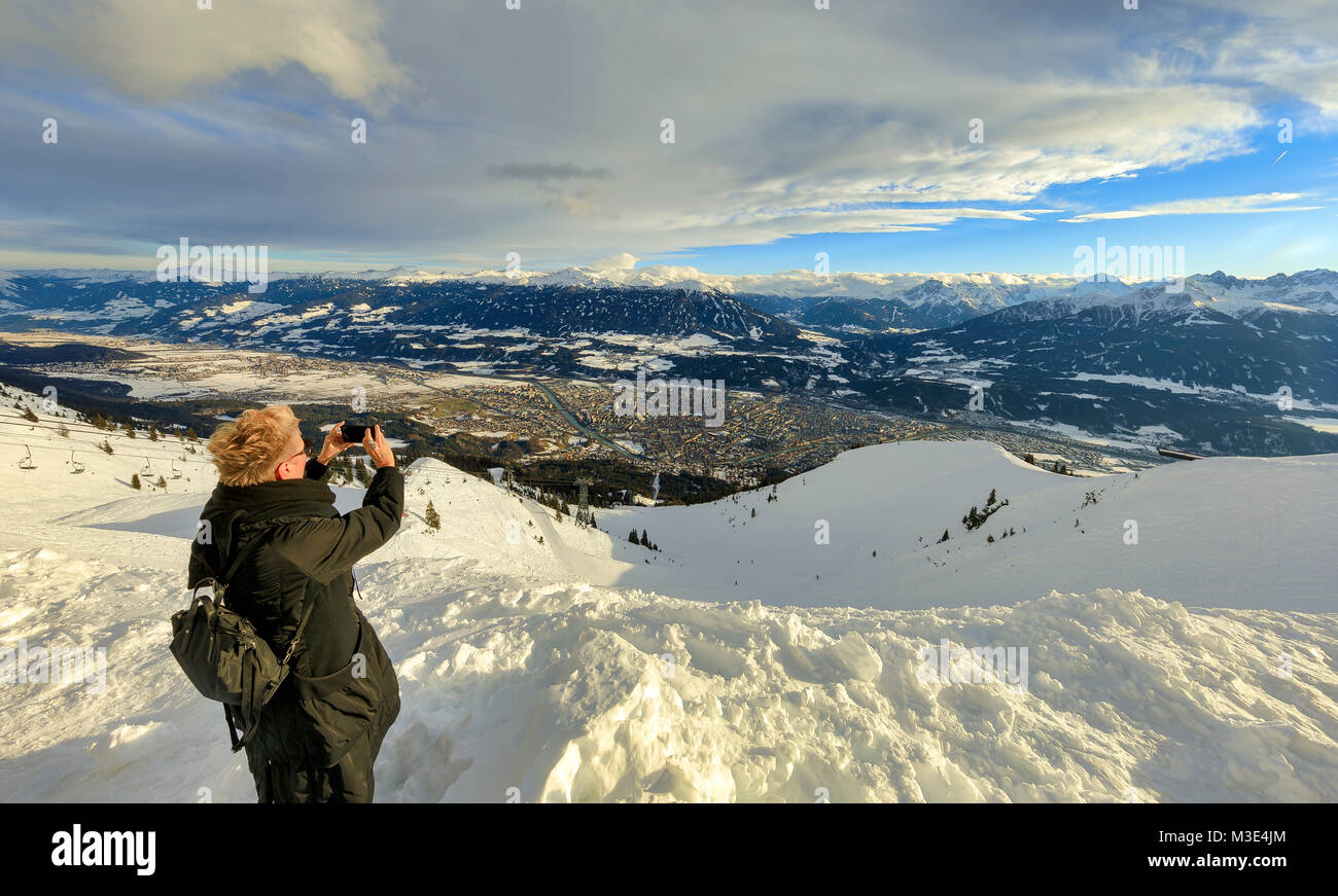 INNSBRUCK, Austria - 26 gennaio: (nota del redattore: latitudine di esposizione di questa immagine è stata aumentata digitalmente.) un turista prende una foto della città e delle Alpi al Monte Seegrube on gennaio 26, 2018 a Innsbruck, Austria. Foto Stock