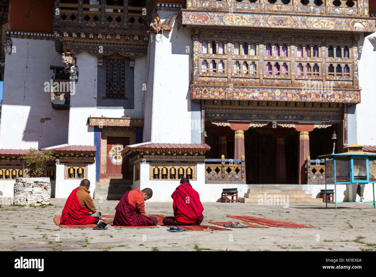 Phobjikha, Bhutan. I monaci buddisti seduto nel cortile del monastero Gangte Goemba (). Foto Stock