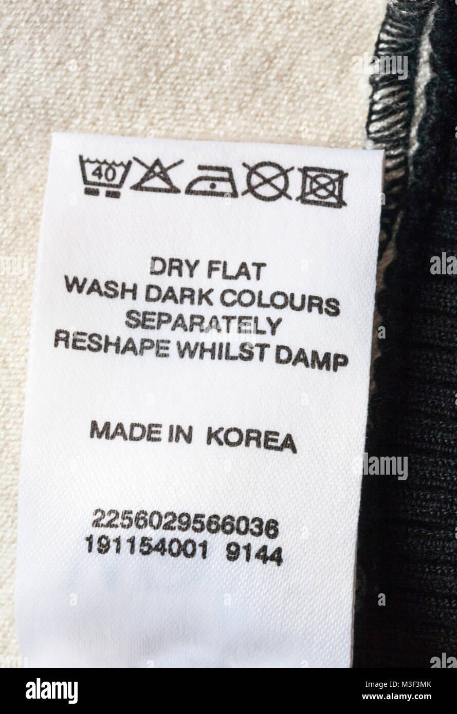 Lavare le istruzioni di cura e i simboli sull'etichetta del capo di abbigliamento abbigliamento made in Corea - piatto secco lavare i colori scuri separatamente mentre cambia forma umida Foto Stock