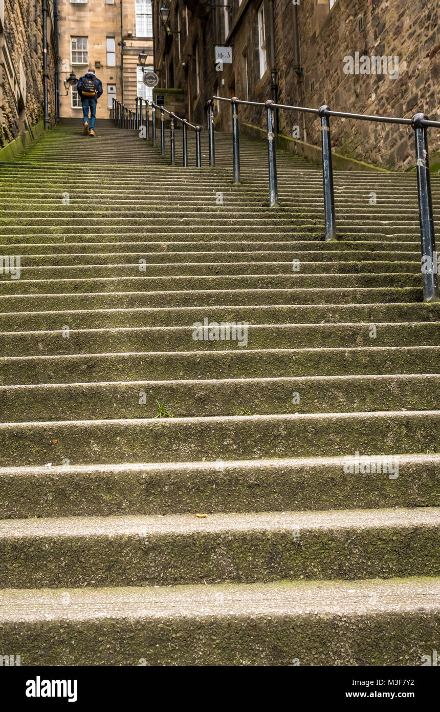 Uomo che cammina fino ripide scale di pietra in un vicolo o stretto passaggio, Warriston vicino, Cockburn Street, Edimburgo, Scozia, Regno Unito Foto Stock