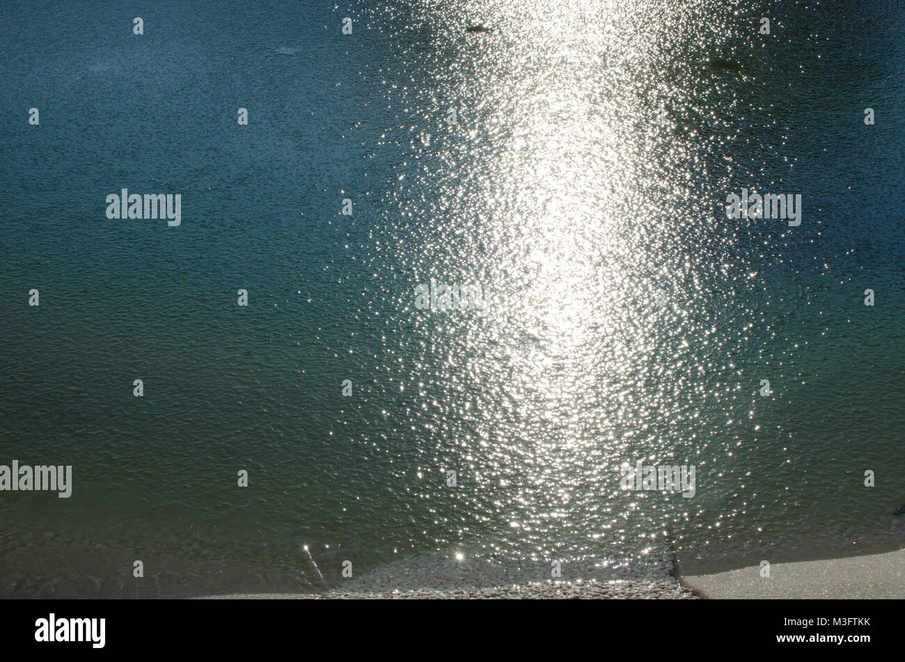 Dettaglio di riflessione della luce solare in acqua congelata sulla giornata invernale, ghiacciato e texture di sfondo brillano Foto Stock