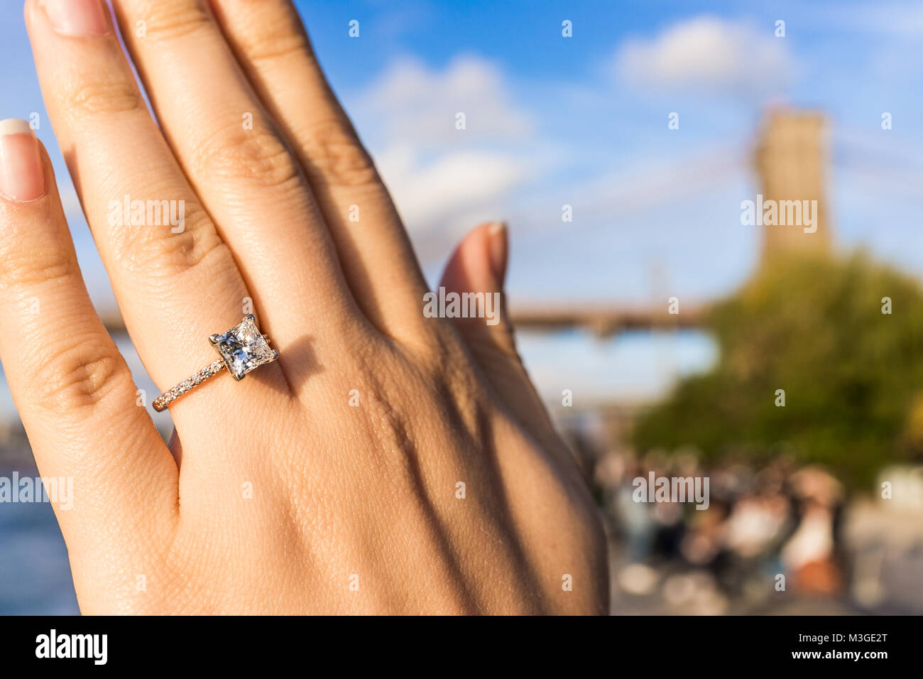 Giovane donna la mano con diamante anello di fidanzamento di taglio  princess, oro al di fuori