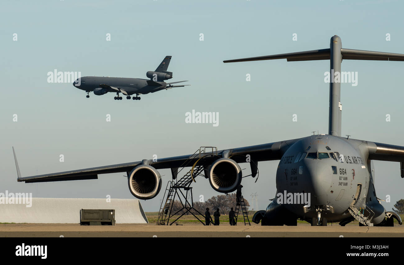 Una KC-10 Extender aeromobile da base comuneGuire-Dix Mc-Lakehurst, N.J., si prepara a terra come Travis Air Force Base aviatori preforma di manutenzione su un C-17 Globemaster III aeromobile come il settantacinquesimo anniversario del kickoff di celebrazione è che si verificano in un hangar vicino a Travis Air Force Base, California, 8 febbraio 2018. La celebrazione featured inaugurale della inaugurazione del settantacinquesimo anniversario logo su un C-17 Globemaster III. Travis sta celebrando 75 anni come strategico importante hub logistico per il pacifico e parte integrante del potere globale proiezione per la forza totale. (U.S. Air Force foto di Master Sgt. Joey Swaffo Foto Stock