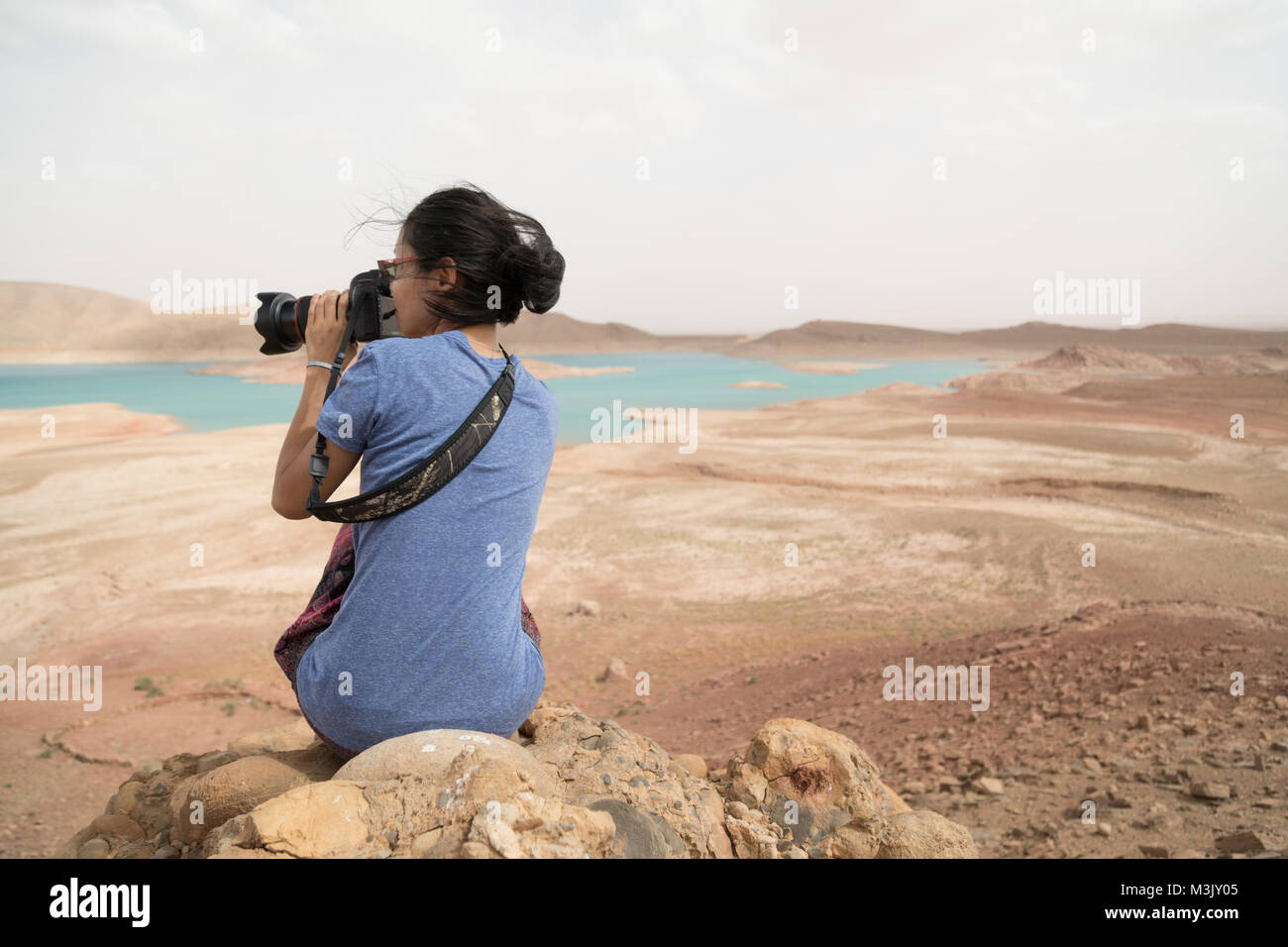 Asian giovane donna a scattare foto Canon EOS 5D Mark IV vista lago pittoresco paesaggio blu-turchese Marocco Foto Stock