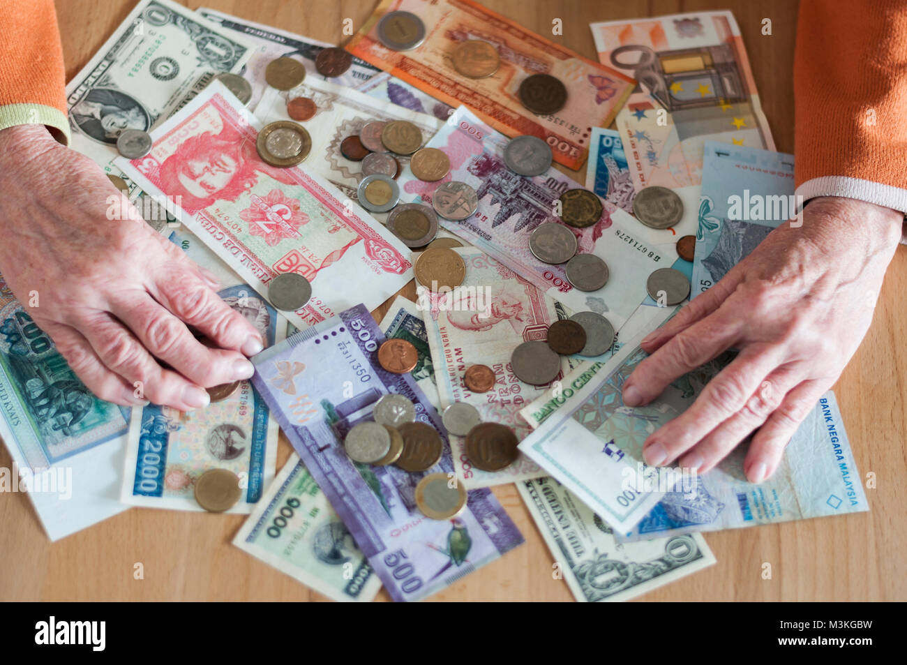 Haende von Seniorin mit verschiedene Geldscheine und Muenzen auf einem Tisch. Foto Stock