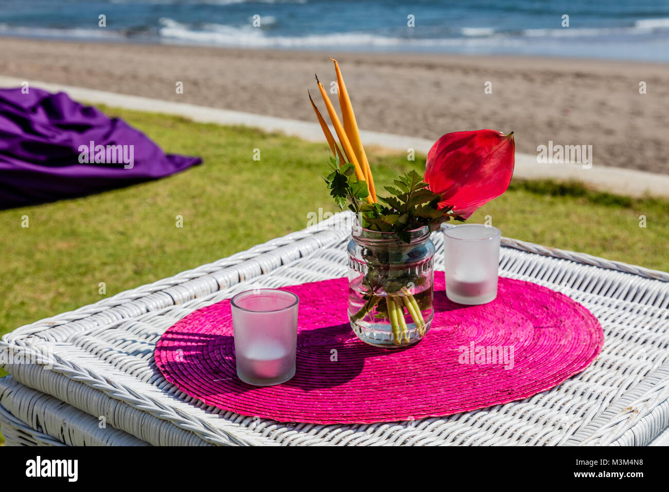 Parte colorata setup vicino all'oceano, tabelle, candele e bouquet di fiori, Bali, Indonesia Foto Stock