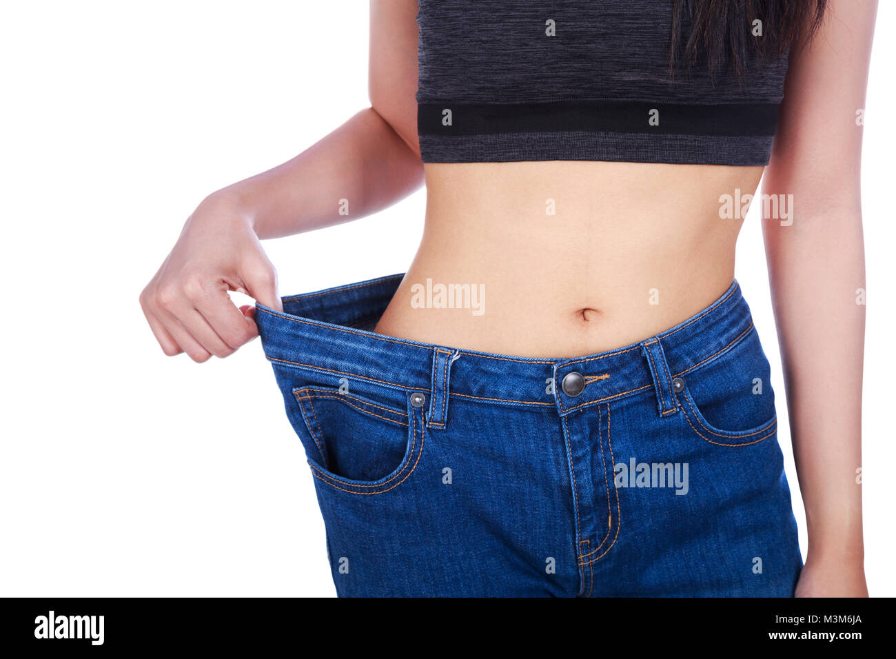 Close up della donna mostra la sua perdita di peso e di indossare i suoi vecchi jeans isolato su uno sfondo bianco Foto Stock