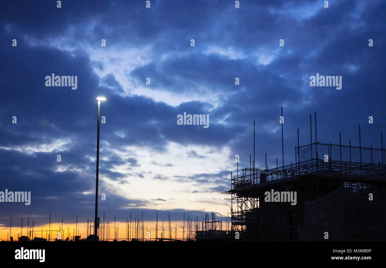 Tramonto su un sito di costruzione in silhouette e una luce di strada Foto Stock