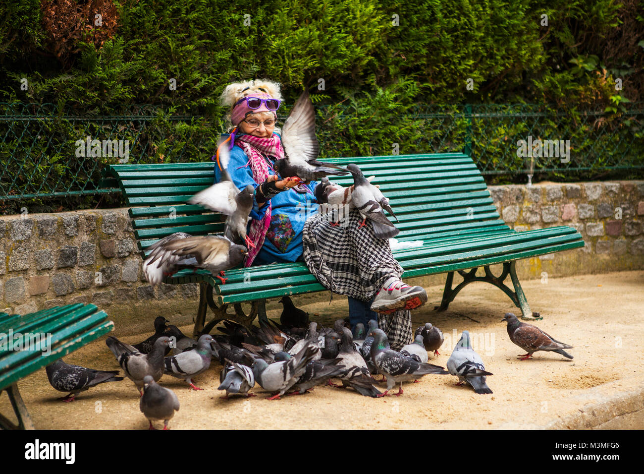 Parigi, Francia - luglio 13,2014: donna anziana alimentare piccioni il pane in un parco giardino pubblico, Parigi, Francia Foto Stock