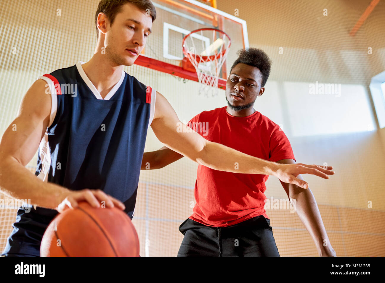 Giocatore di pallacanestro professionale dribbling vicino al cestello di concorrenti Foto Stock