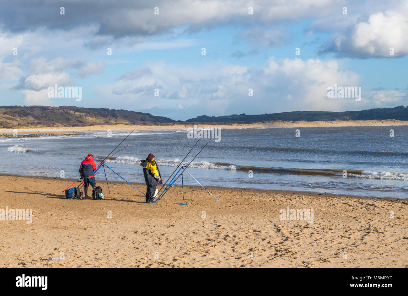 Due pescatori sulla spiaggia di Newton Porthcawl Galles del Sud su una luminosa giornata invernale Foto Stock