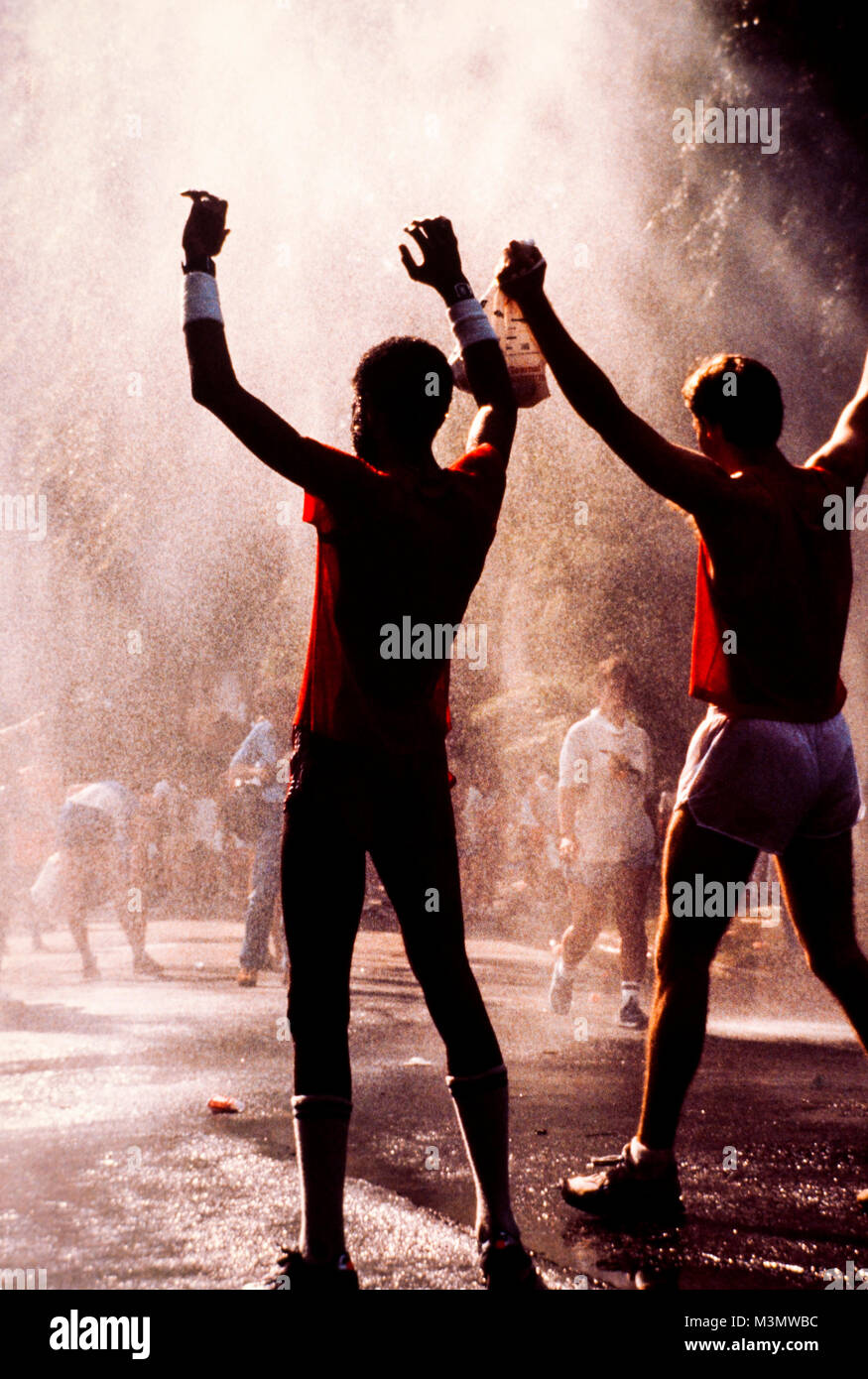 Corridori della maratona raffreddare in uno spruzzo di acqua alla fine della loro corsa Foto Stock