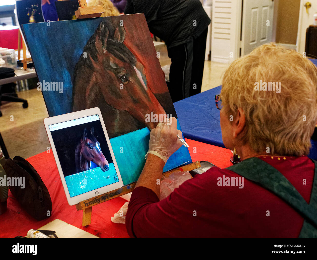 Gli anziani che hanno vissuto una dura ancora rimanere attivi esprimere se stessi nella classe di pittura, Pam Smith utilizza una foto scattata con il suo iPad a dipingere un cavallo di amici. Foto Stock