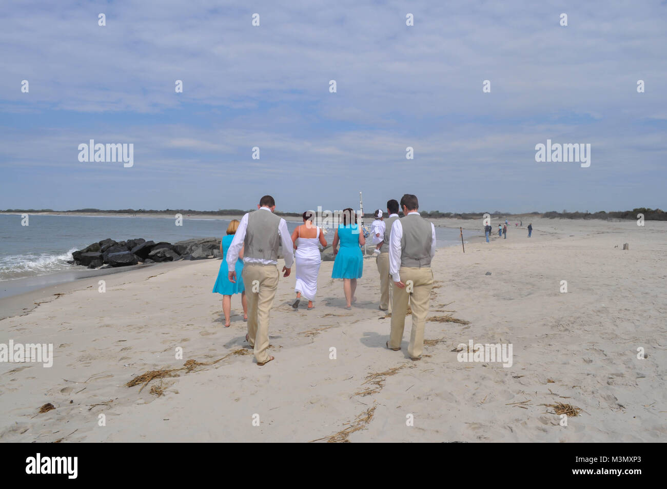 La gente a piedi dopo un matrimonio sulla spiaggia Foto Stock