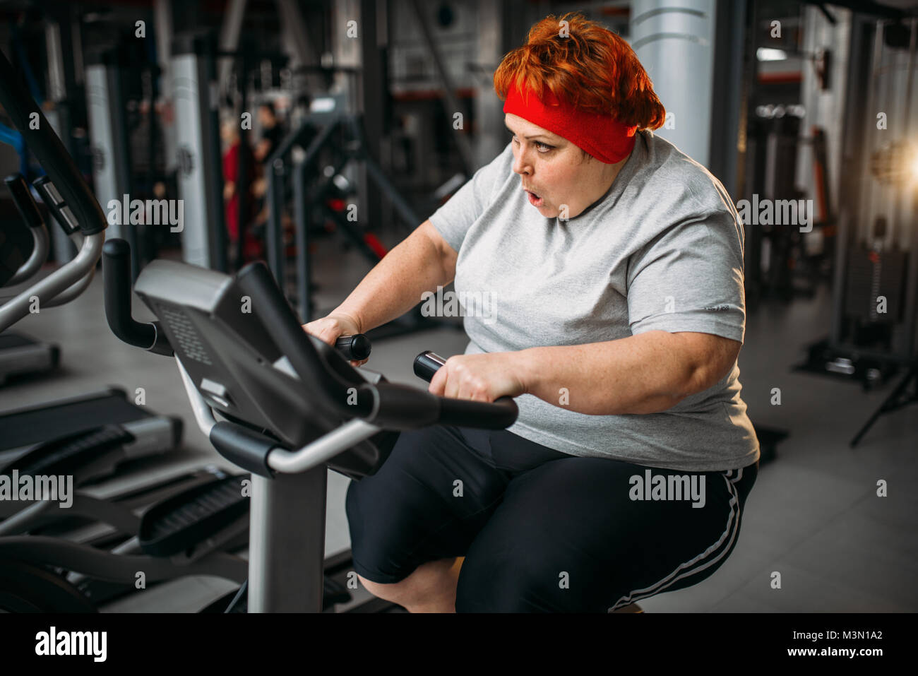 Grasso donna formazione sulla cyclette in palestra. Calorie bruciare, femmina obesi in persona lo sport club Foto Stock
