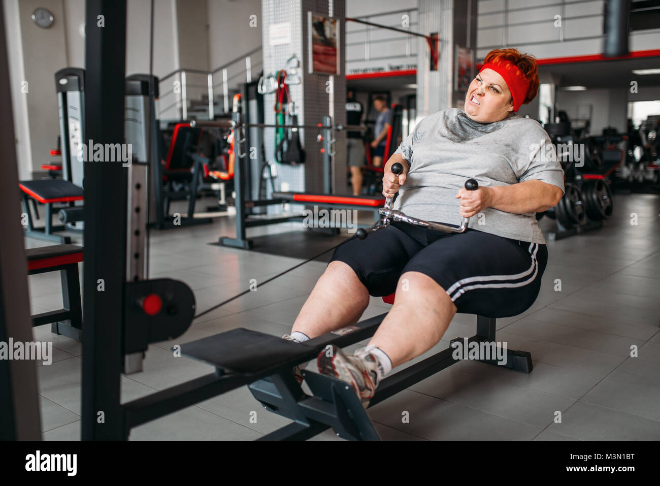 Donna grassa, attiva training sulla macchina ginnica in palestra. Calorie bruciare, femmina obesi in persona lo sport club Foto Stock