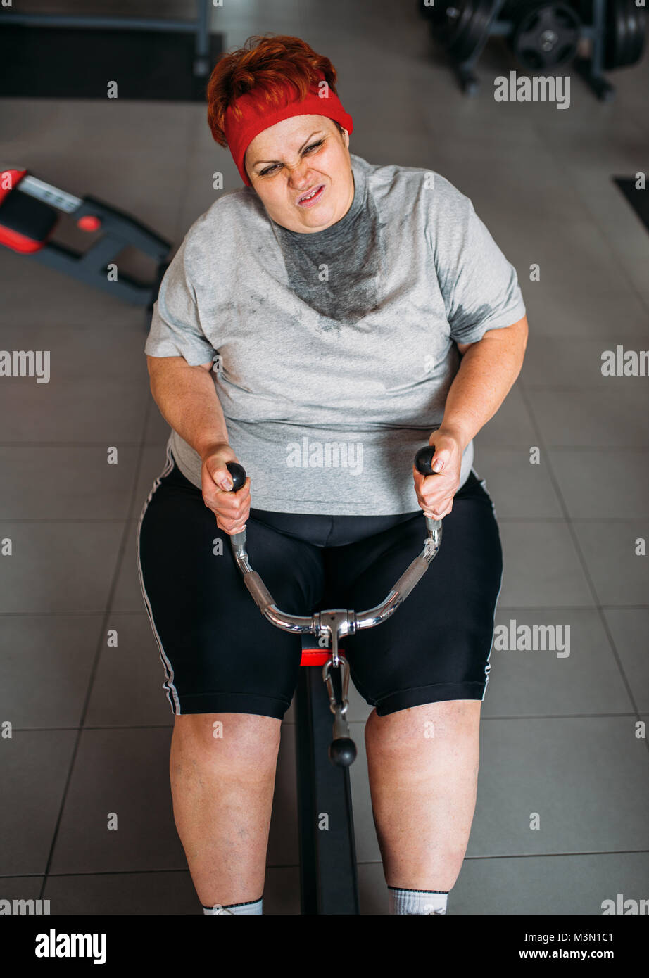 Grasso donna sudate, attiva training sulla macchina ginnica in palestra. Calorie bruciare, femmina obesi in persona lo sport club Foto Stock