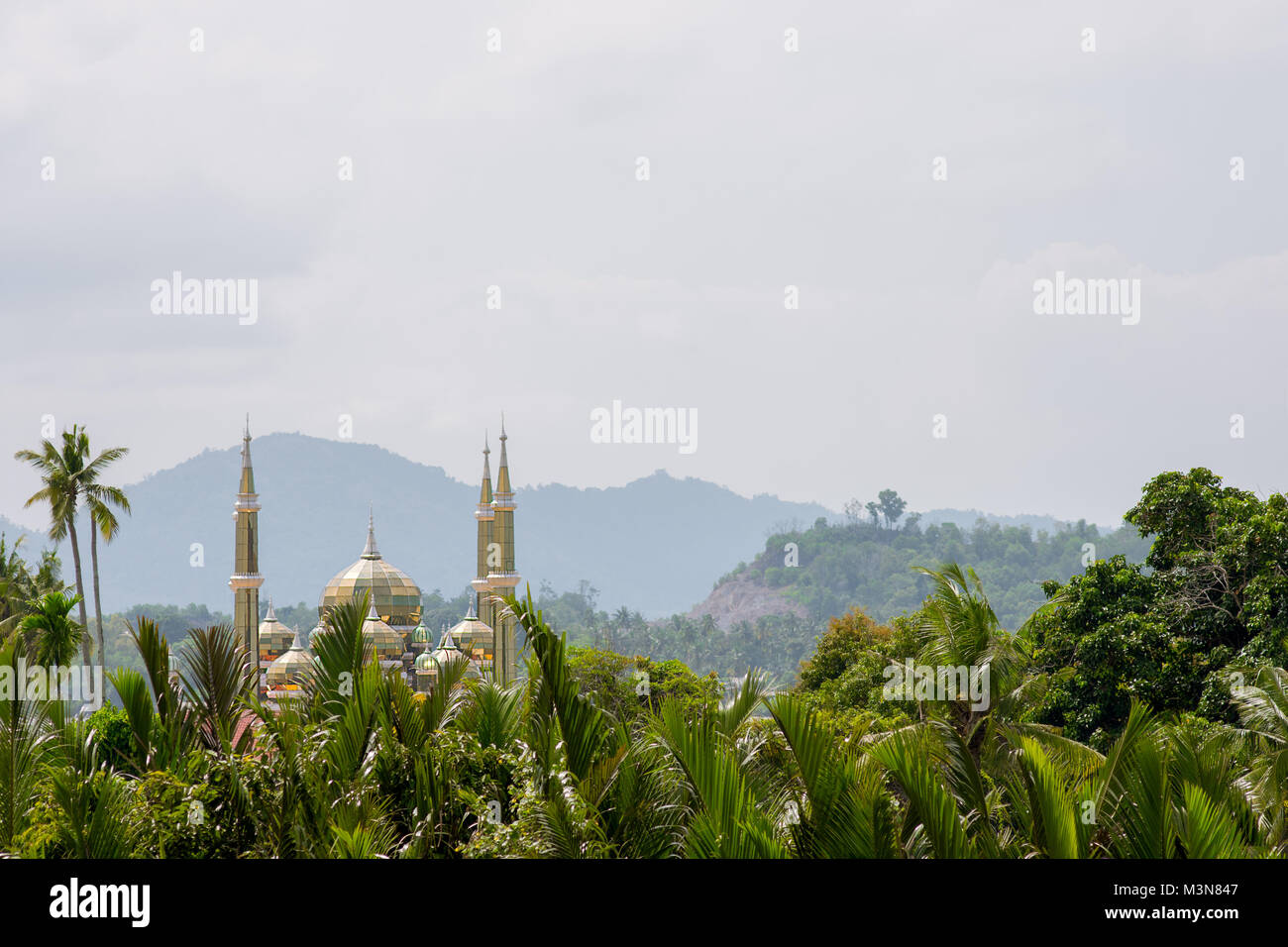 I minareti e la cupola della moschea di cristallo o Masjid Kristal a Kuala Terengganu, della Malaysia che sovrasta una vista in primo piano di palme tropicali. Foto Stock
