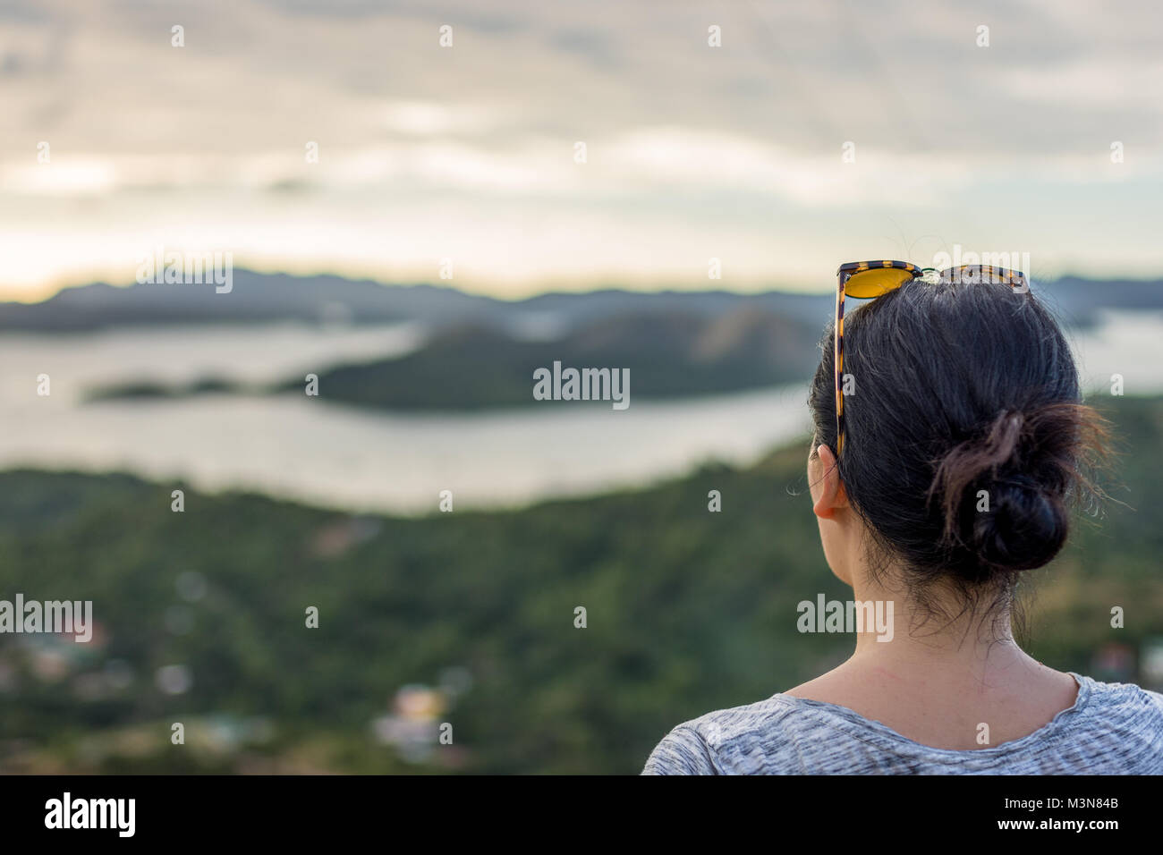 Dai capelli scuri donna prendendo in una vista in elevazione del mare e delle isole intorno Coron, PALAWAN FILIPPINE. Foto Stock
