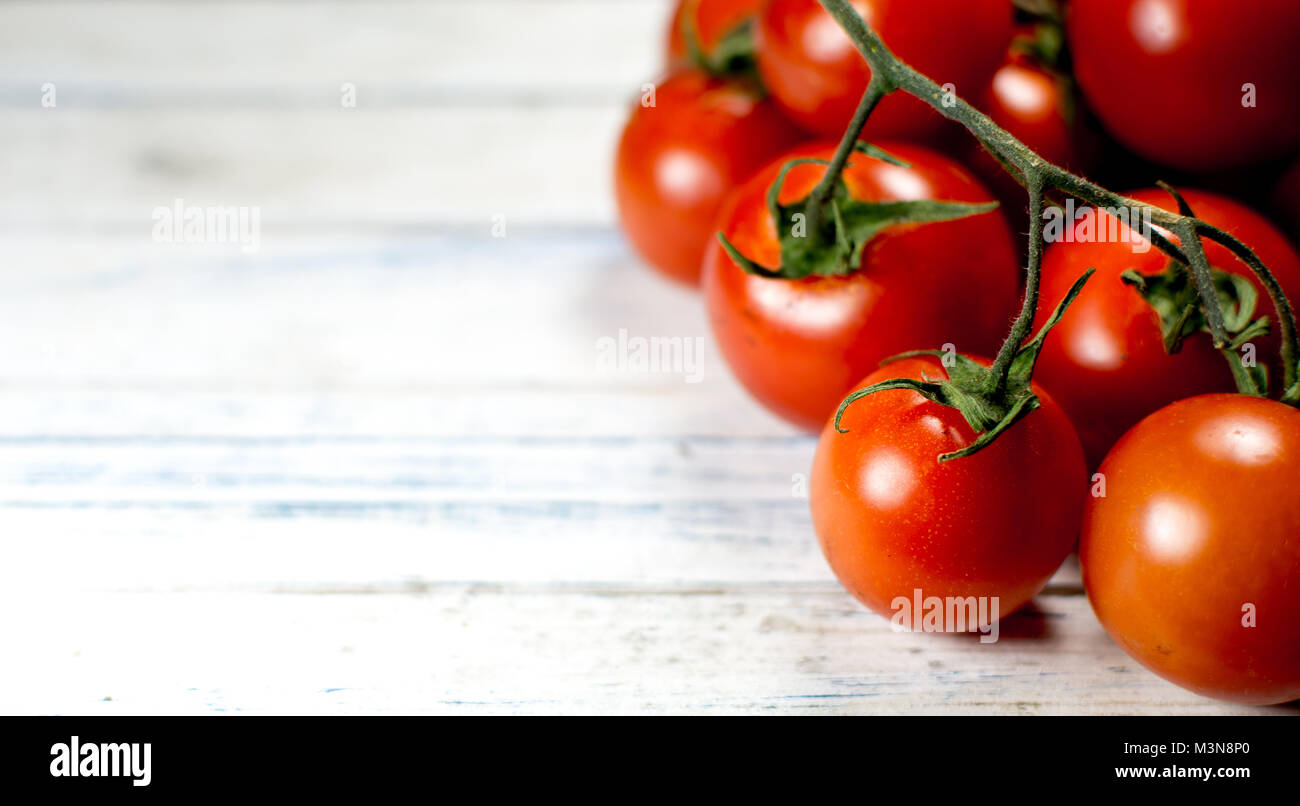 Vite stagionati pomodori ciliegia su una tavola in legno rustico Foto Stock