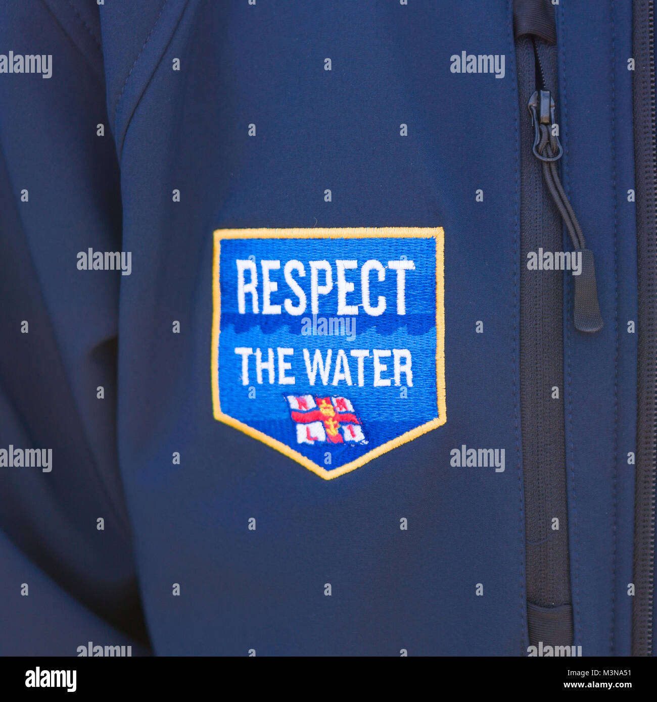 Una chiusura di un RNLI rispetto l'acqua una patch su un blu giacca in vello. Foto Stock