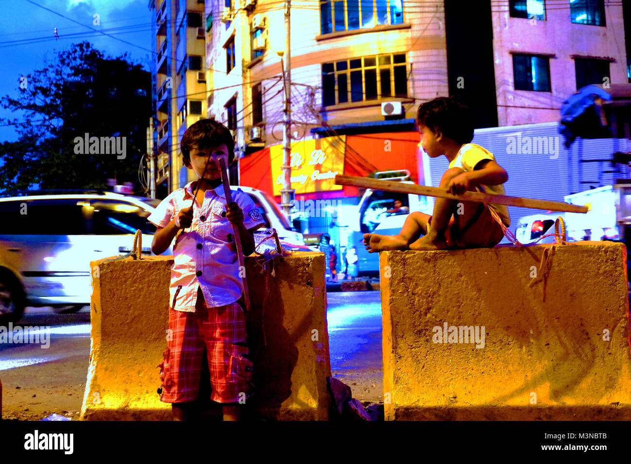 Bambini che giocano sul ciglio della strada accanto al clan sporti in Yangon Myanmar Foto Stock