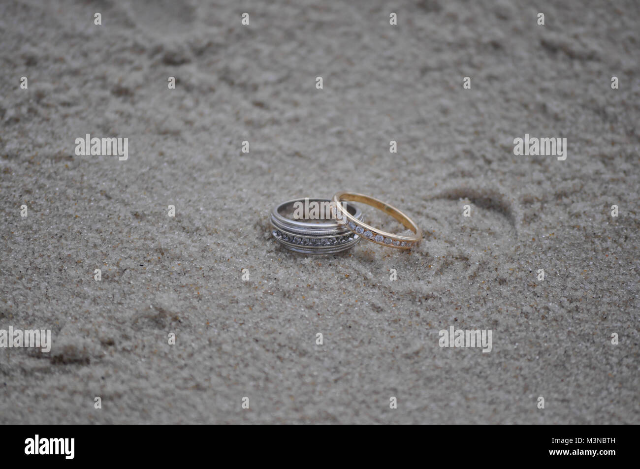 Gli anelli di nozze su una spiaggia di sabbia Foto Stock