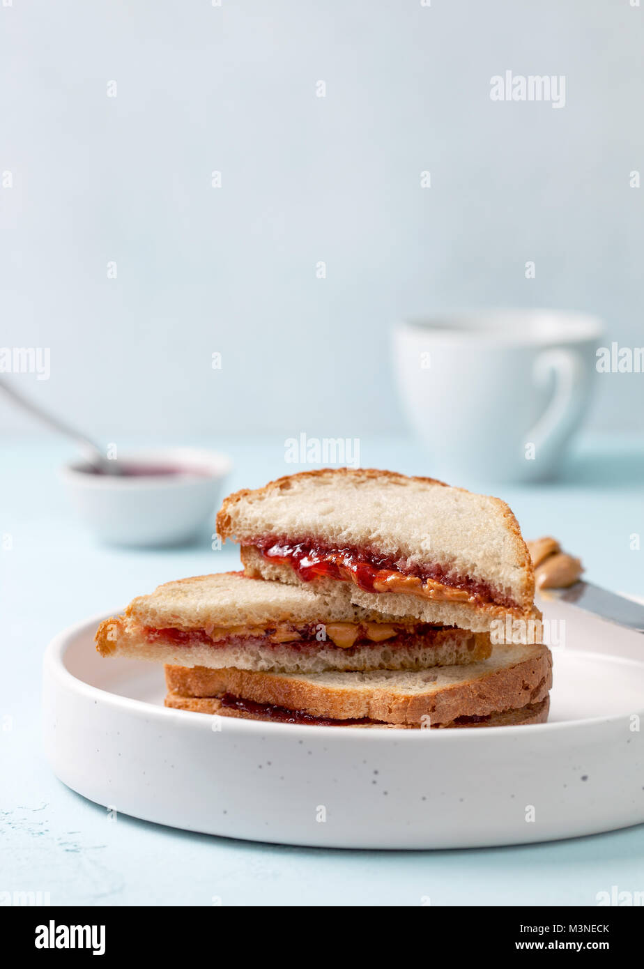 Toast con burro di arachidi e marmellata in un piatto di portata in ceramica bianca su sfondo blu sullo sfondo di calcestruzzo Foto Stock