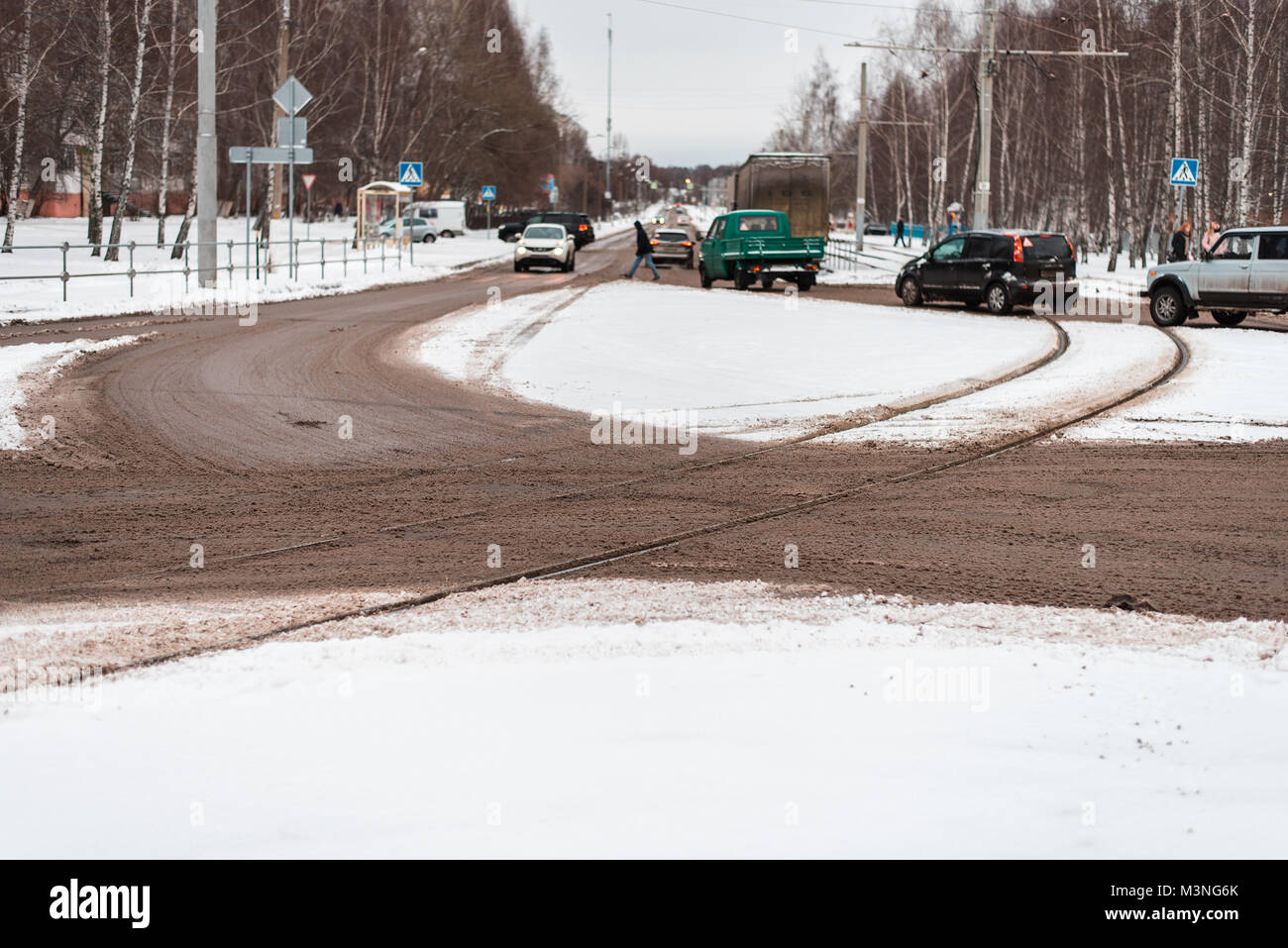 L'inverno nella città di zebra attraversamento pedonale. Le automobili e i tram della città. Sporche tracce di neve della strada le linee di tram. Macchine in movimento. Foto Stock